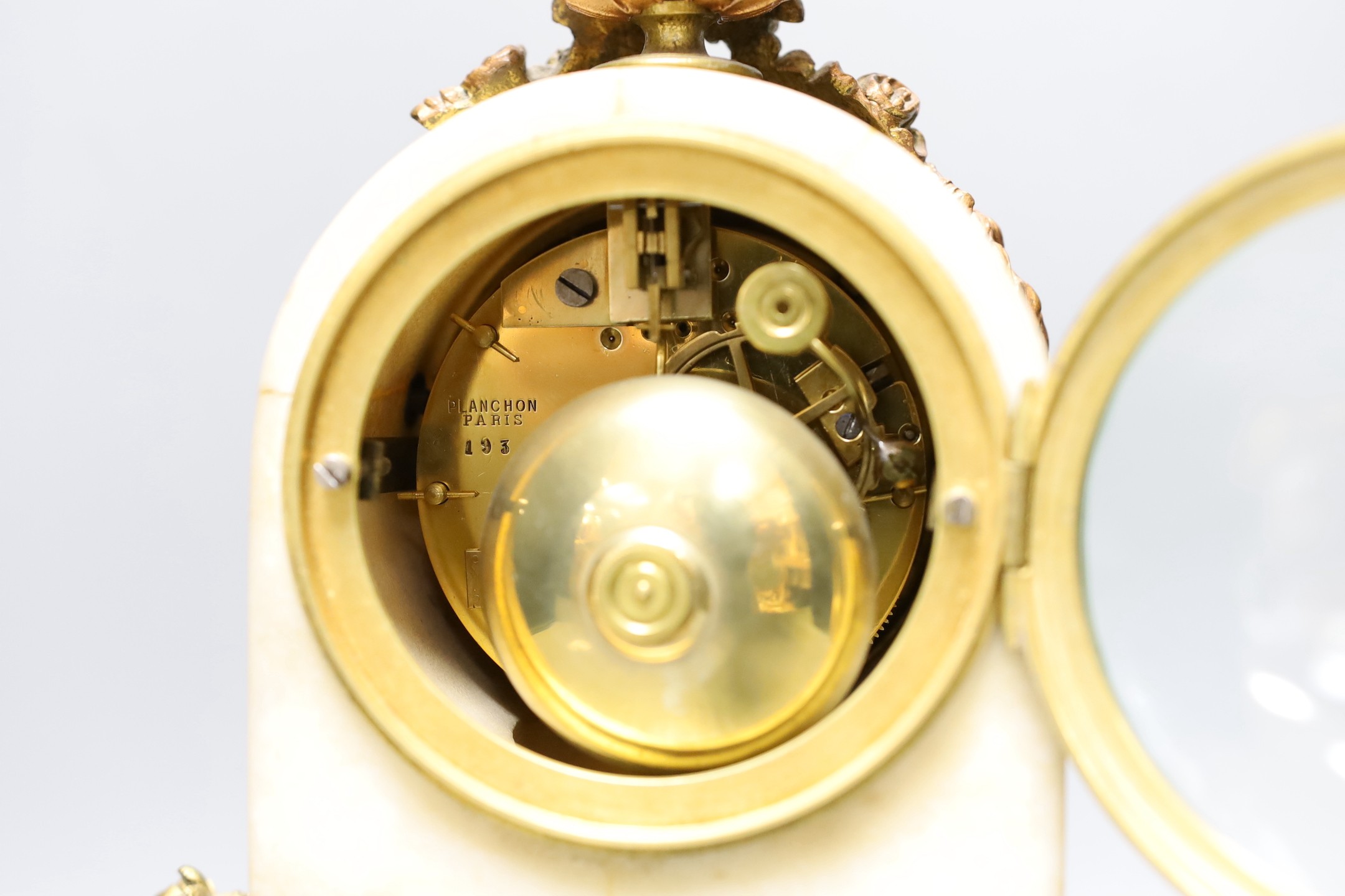 A 19th century French alabaster and phosphur bronze mounted mantel clock with a painted demi lune inset. 33cm tall